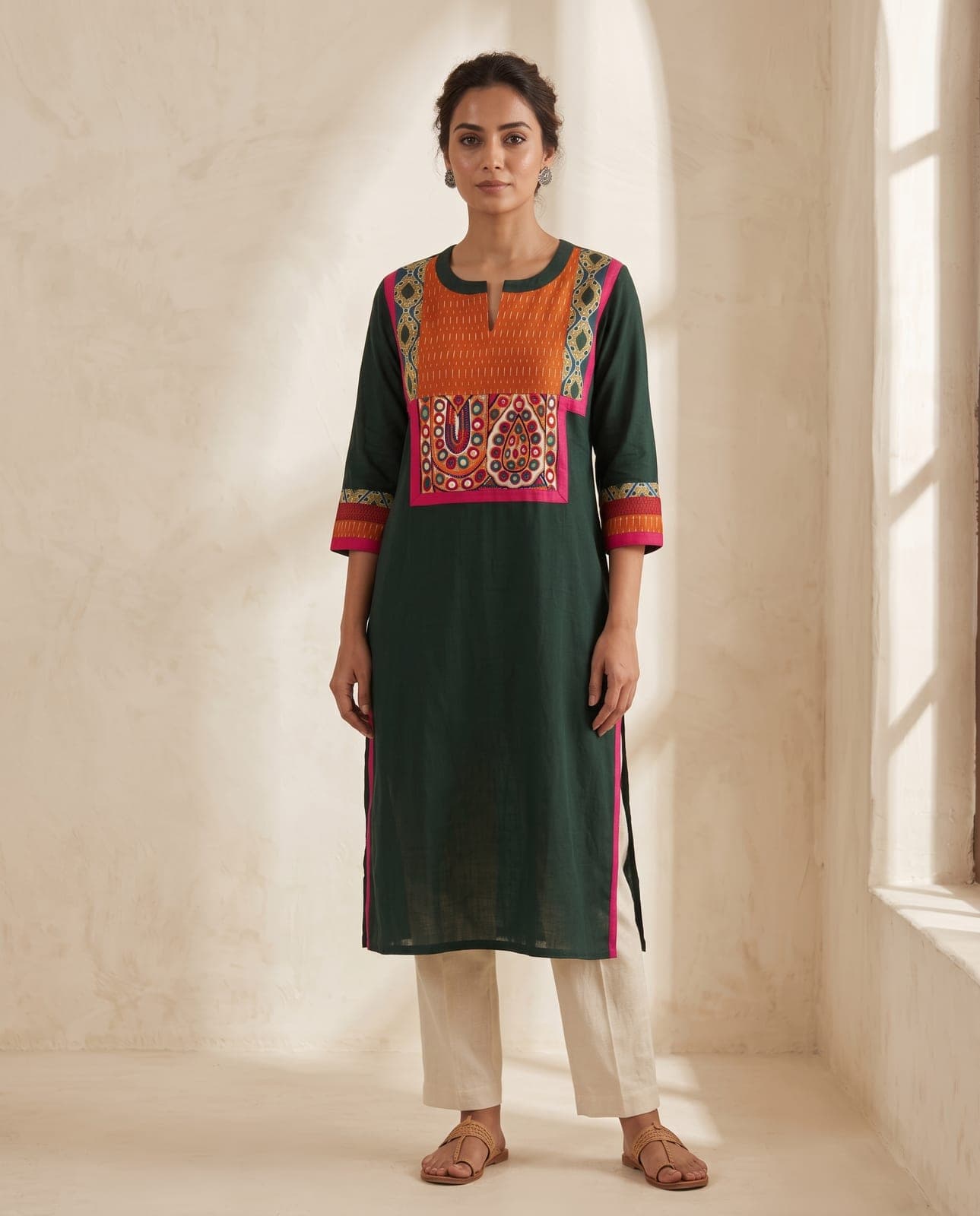 Styled image of a model wearing the deep green Albeli kurti with an orange mirrorwork yoke