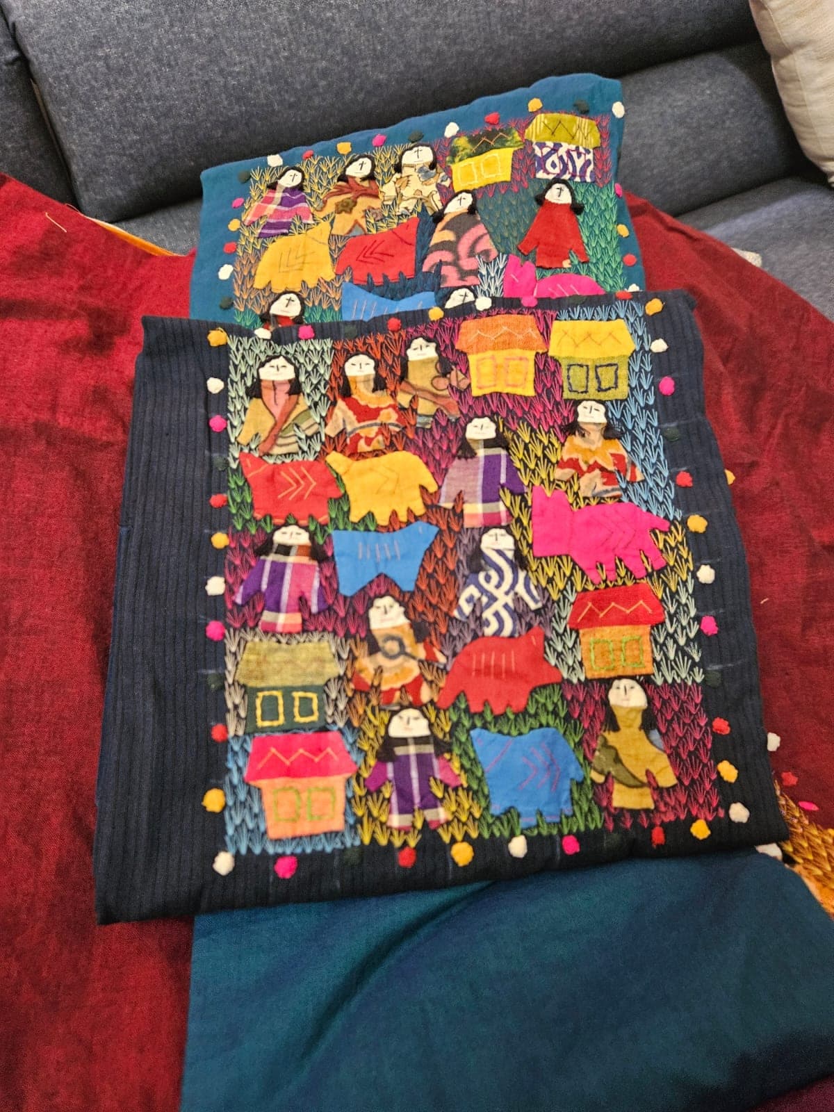 The patchwork panels of people, animals and houses laid out on fabric before stitching